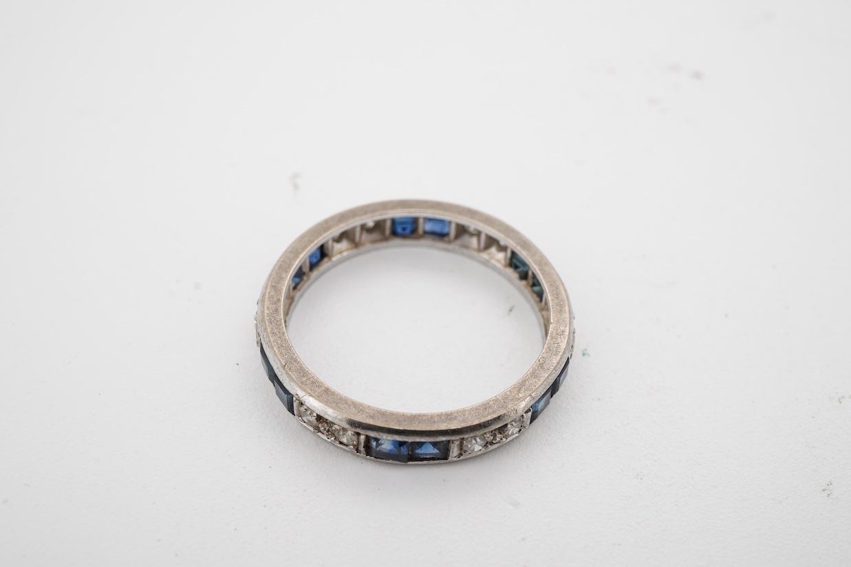 A white metal, twelve stone diamond and twelve stone sapphire set full eternity ring, size N, (remnants of an 18ct hallmark?).